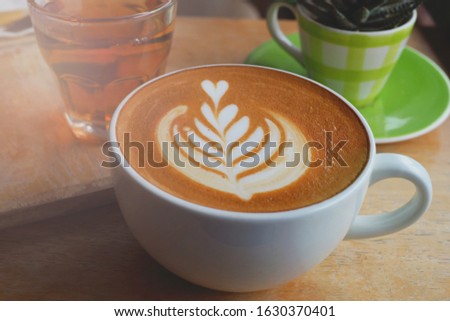 Cup of latte drink or coffee on brown wooden tray served in a restaurant, selective focused picture of beverage for refreshment after lunch, latte art, cappuccino to go with breakfast, coffee cup   