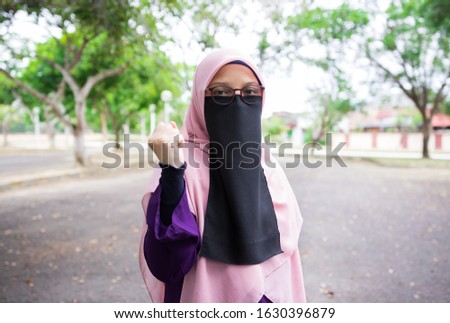Portrait of pretty hijab women wearing niqab showing succeed gesture outdoor.