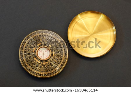 Old vintage chinese compass used in feng shui, golden item with cover, on black background. Studio, copy space.