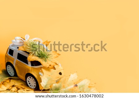 toy car bursts through torn paper, autumn on yellow paper. The concept of a cozy and modern autumn. Trend yellow background. Flat lay, top view, copy space