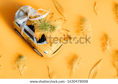 toy car bursts through torn paper, autumn on yellow paper. The concept of a cozy and modern autumn. Trend yellow background. Flat lay, top view, copy space
