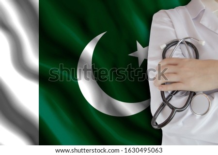 The concept of the level of medicine in the country, the salary of a doctor, the incidence rate in the country. Doctor holds a stethoscope on the background of the flag of Pakistan