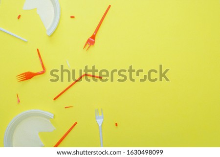 Plastic garbage on a yellow background. Disposable forks, plates, tubes. Copy space.