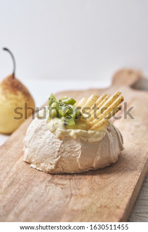 Pavlova cake with cheese cream, lemon Kurd, kiwi and pear.