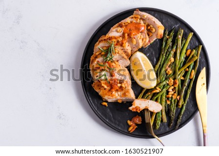 Grilled chicken breast with grilled asparagus and lemon slice on stone background . Paleo diet. Royalty-Free Stock Photo #1630521907
