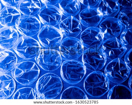 A close up photo of a sheet of blue plastic bubble wrap. Patterns of circular bubbles form repeating rows and columns