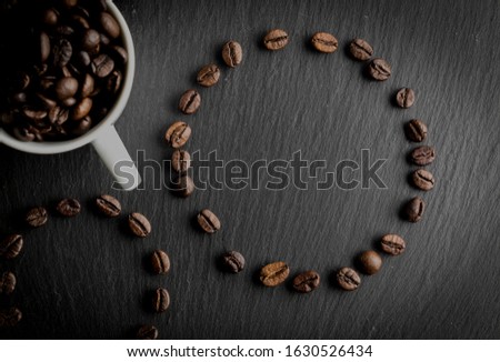 cup of coffee with coffee seeds shaped like circles on the bottom of stone and space for advertisement, zenith, dark food