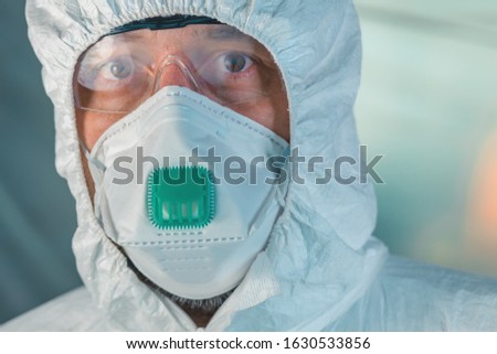 Portrait of male virologist with protective mask, goggles and clothing looking at camera, selective focus Royalty-Free Stock Photo #1630533856