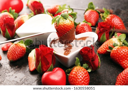 Valentine Chocolate fondue melted with fresh strawberries and dark and white chocolate. Red roses and sugar hearts for Valentines Day. dessert for love