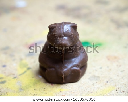 A brown chocolate-colored bear sits on a wooden surface. Frontal view