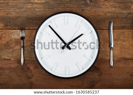 Concept. 10 euros in a white plate, knife and fork on a wooden background. Reverse.