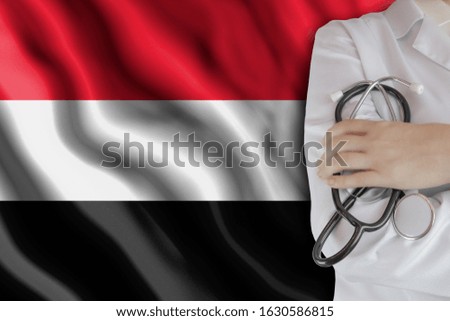 The concept of the level of medicine in the country, the salary of a doctor, the incidence rate in the country. Doctor holds a stethoscope on the background of the flag of Yemen
