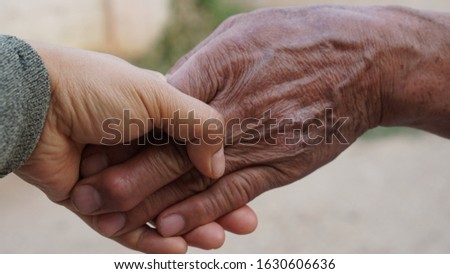 A wonan's hand is touching the old man's hand with care 