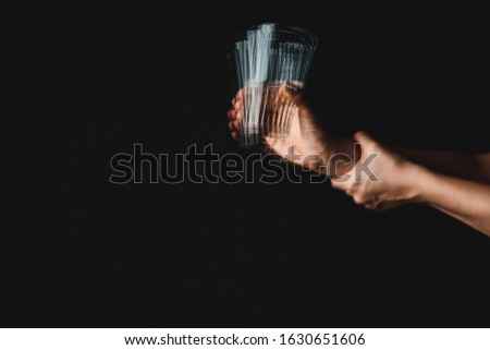 Woman suffering from Parkinson syndrome with glass of water against dark background Royalty-Free Stock Photo #1630651606