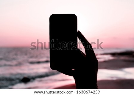 Girl is taking a sunset photo on the phone