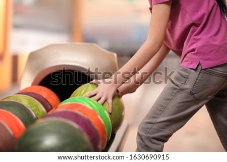 Little girl taking ball in bowling club, closeup