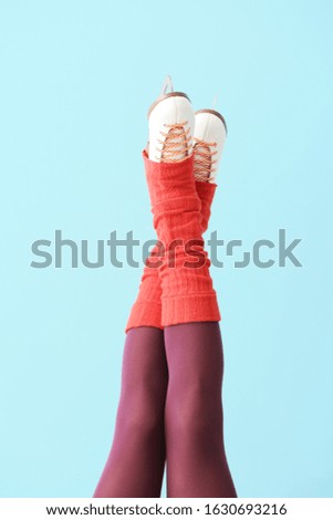 Young woman in ice skate shoes on color background
