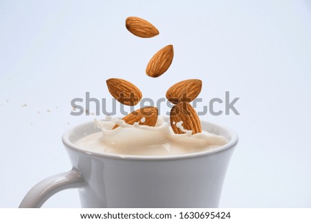 Closeup milk splash with almonds nut  on white background.