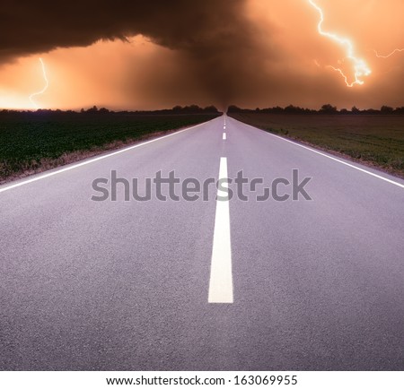 Driving on empty road towards the oncoming storm