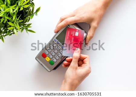 Contactless payment, paypass. Hand hold bank card near terminal on white background top-down