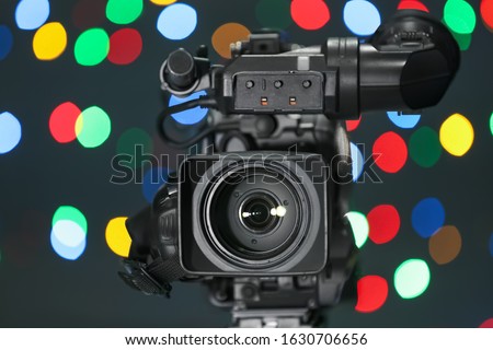 Modern video camera against blurred colorful lights