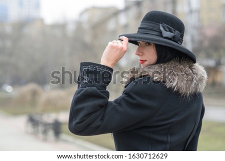 A nice girl in a beautiful gray coat and hat walks in the park on a cold autumn  winter day. Portrait photography.