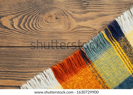 Checkered colorful plaid on wooden background. Cozy winter home.