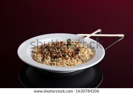 yakisoba on a plate with a dar red background