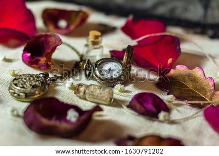 A pocket watches and rose petals on the table