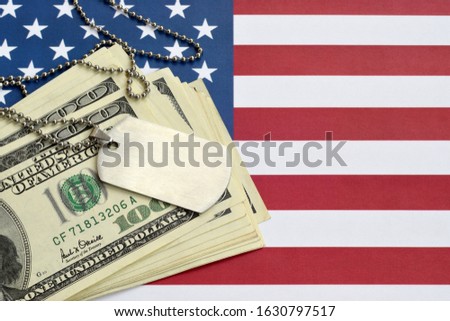 Army identification medallions and dollar bills on United states flag. Military pension, salary in the army or military insurance Royalty-Free Stock Photo #1630797517