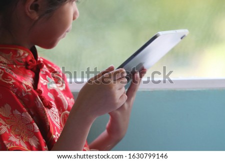 Asian cute girl wearing Cheongsam she searching the entertainment technology with digital tablet loneliness at home with out her parent take care use social media