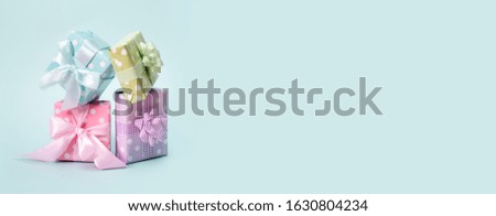 Holiday flat lay with gift boxes wrapped in colorful paper and tied with bows on blue background, decorated with confetti. Birthday, Christmas and sale concept, top view