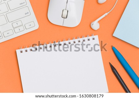 Modern office desk workplace with blank notebook and supplies. Copy space on color background. Top view. Flat lay style.
