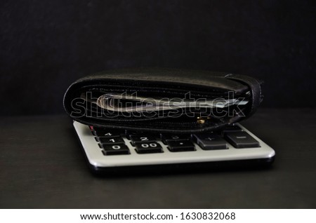dollars in a black men's wallet and a calculator on a black background. Close-up. Business concept.
