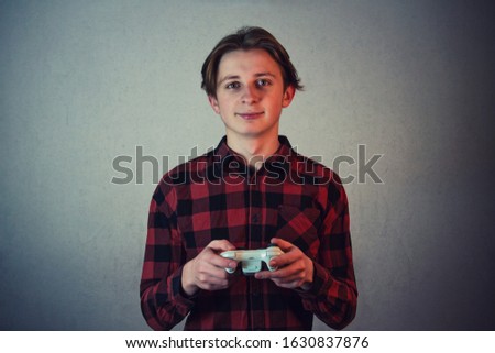 Joyful teen boy playing video games isolated on grey wall background. Excited adolescent holding joystick console looking attentive to camera, try to win, having fun in the virtual world.