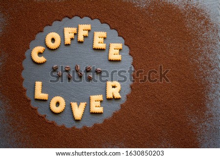 Dark gray slate background with dusted flower decoration in the shape of a flower with biscuit letters for coffee lovers and for an energizing breakfast and good morning