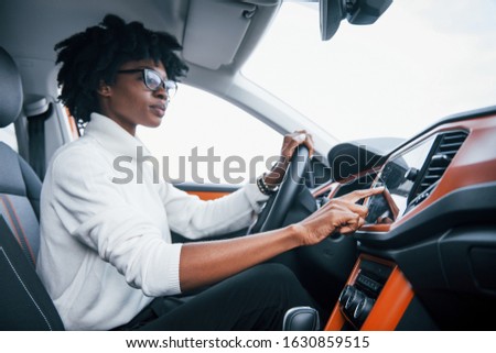 Young african american woman sits inside of new modern car.
