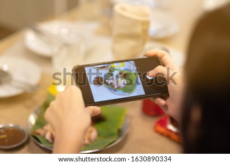 A girl take a picture some food by smartphone in Thai restaurant
