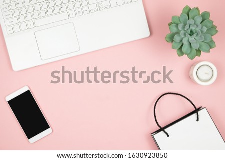 Shopping Online Concept. Womens hands with phone and laptop on pink background. Top view, copy space.