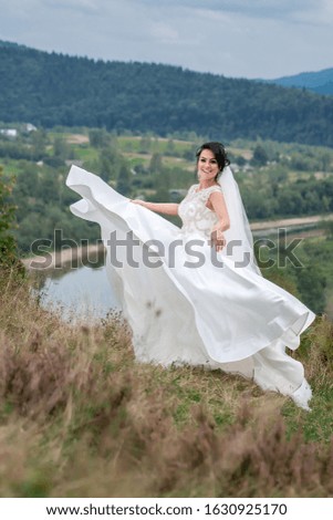 Wedding day. stylish brunette in wedding dress posing in the mountains near the river.