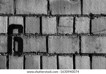 Number 6 in stencil on rusty brick wall in black and white. Abstract background and texture for design.