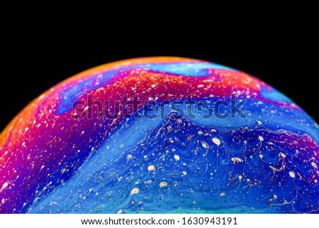 Rainbow soap bubble on an isolated black background. Close-up of the colorful surface. Poster blank