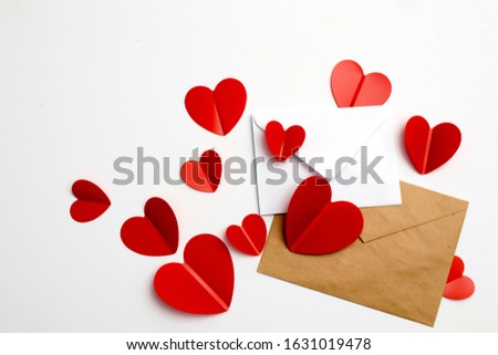 Greeting card for Valentine's Day. Envelopes on a white background and red plastic hearts. Copy space.