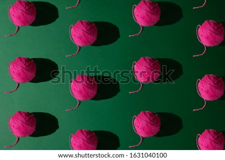 Seamless pattern of pink yarn on green background; flat lay