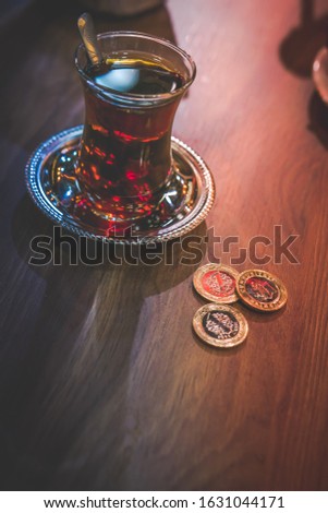 Creative background photo of turkish traditional drink - black tea from Rize. And three turkish coins left on the wooden table-payment. Cheap trabel destination -Turkey.