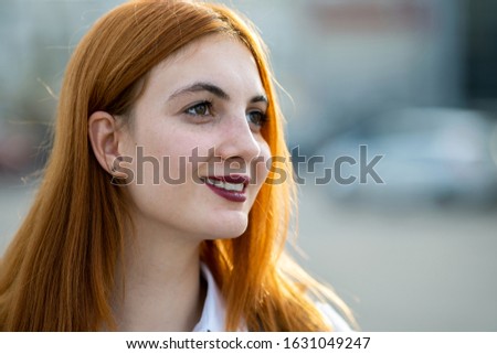 Closeup face portrait of a smiling teenage girl with red hair and clear eyes.