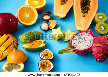 food, summer and healthy eating concept - different exotic fruits on blue background