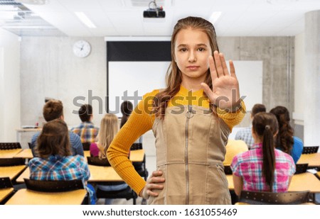 school, education and people concept - teenage student girl making stopping gesture over classroom background