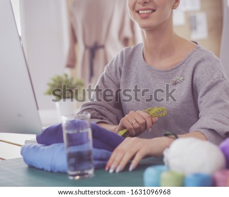 Fashion designer woman working in studio, sitting at thhe desk