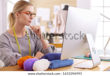 Woman designer in workshop looking at computer screen
